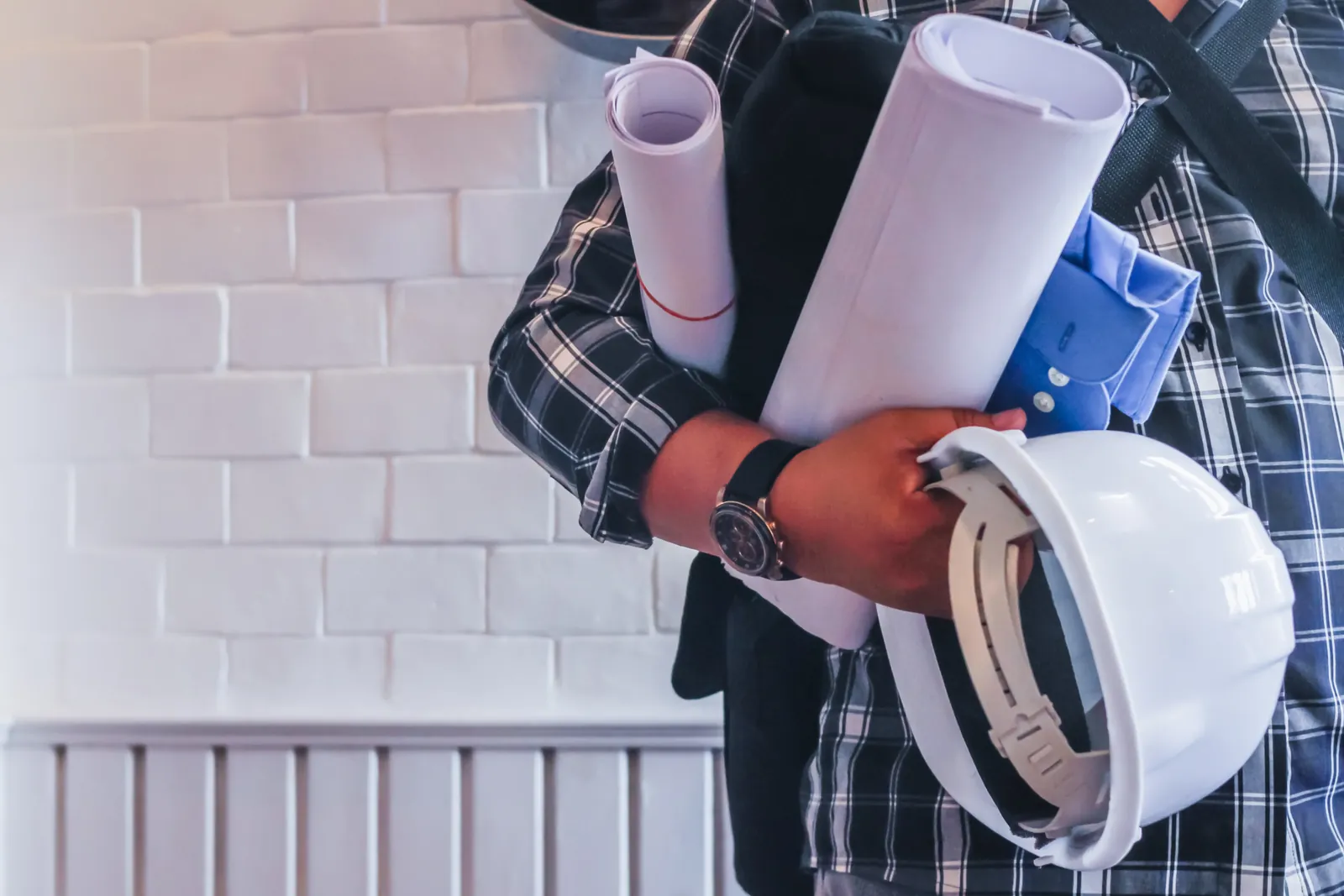 Engenheiro com plantas e capacete branco em mãos